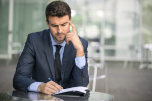 Focused businessman thinking and writing outside office